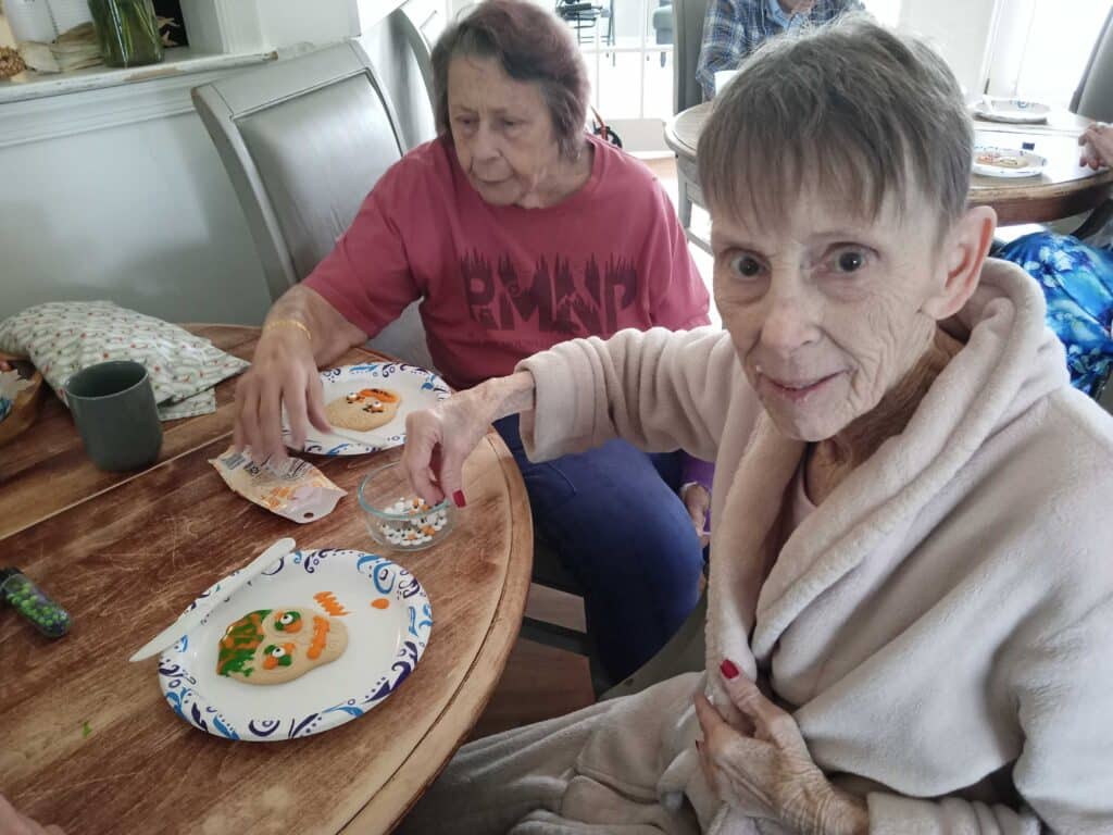 Two senior women at a table decorating the cockie