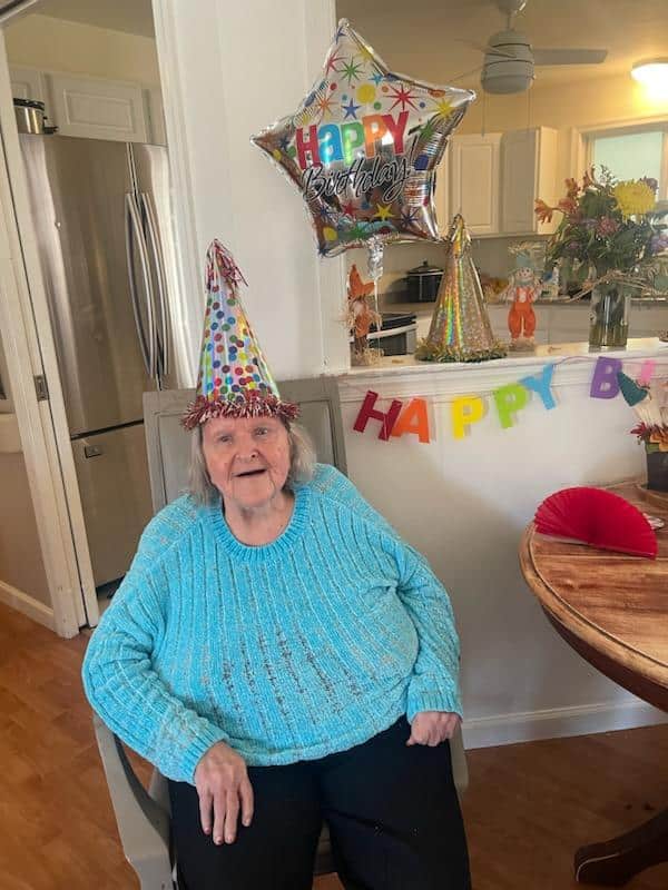 An elderly woman dons a birthday hat