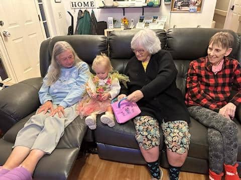 A young girl sits on a couch with three older women