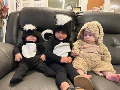 Three children in colorful animal costumes happily sitting together on a couch