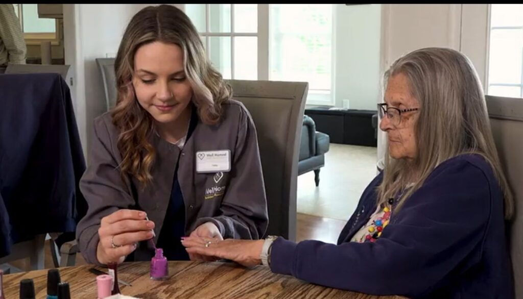 A woman applies nail polish to an older woman's nails